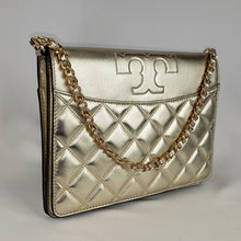 Load image into Gallery viewer, Shimming gold clutch Gold toned hardware featuring a chain strap interwoven with leather Tory Burch &quot;T&quot; accent  100% embossed calfskin leather Light tan fabric interior Snap closure with top flap 2 interior compartments separated by slim, slip compartment  Adjustable, detachable shoulder strap 10.5” x 8” x 1.5” Chain drop: 7&quot; Shoulder strap drop: 21.5 - 24.5&quot; Product number 192485331639 Made in China