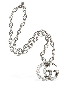 The Gucci GG Marmont Crystal Necklace In Silver is a rare and unique piece by none other than Gucci. A crystal encrusted GG pendant hangs from a delicate, intricately carved chain. A feline head charm hangs from the clasp. 