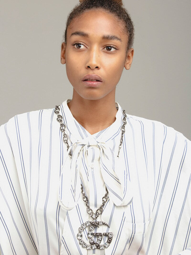 The Gucci GG Marmont Crystal Necklace In Silver is a rare and unique piece by none other than Gucci. A crystal encrusted GG pendant hangs from a delicate, intricately carved chain. A feline head charm hangs from the clasp. 