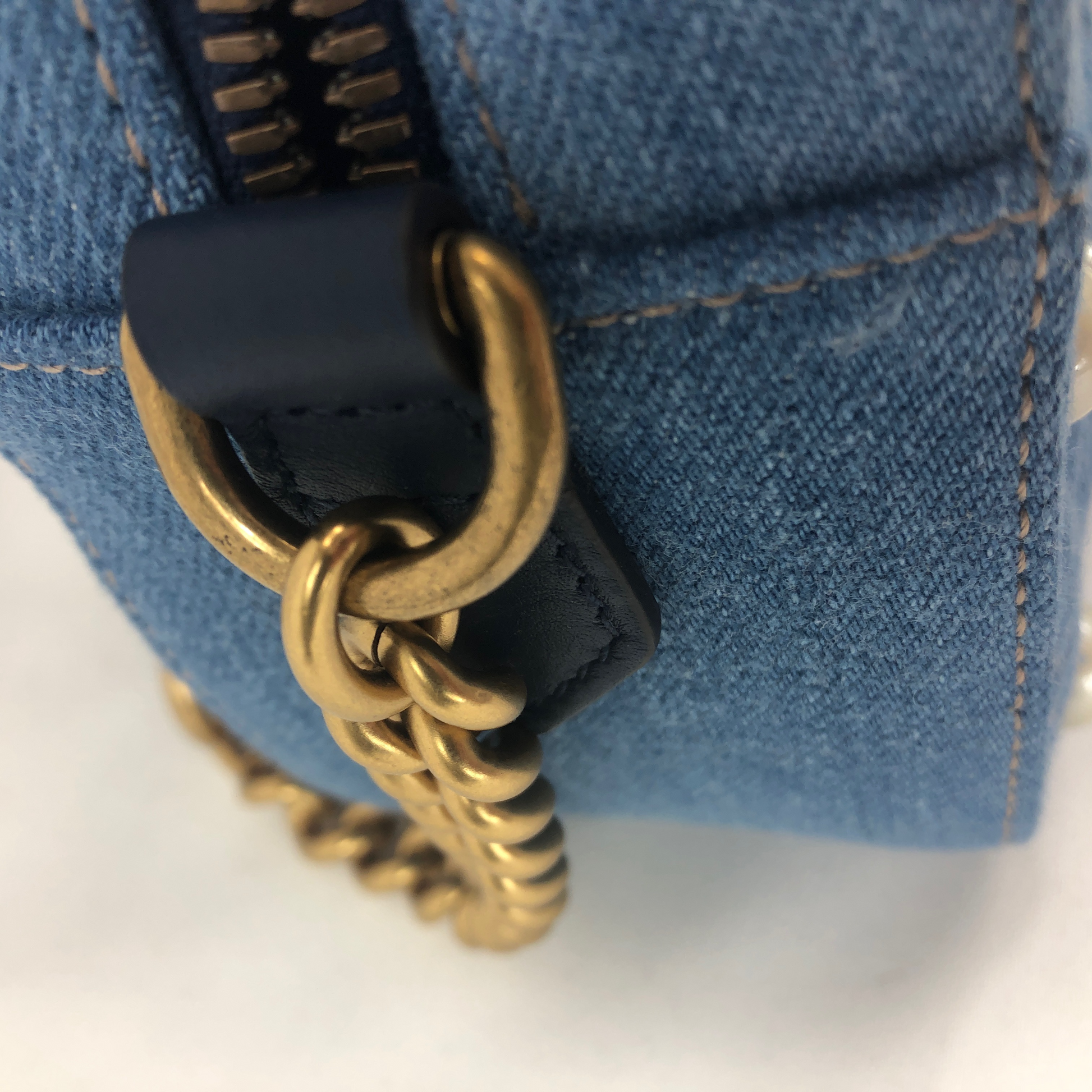 The Gucci Marmont Pearl Crossbody Bag in Denim is a modern take on a classic look. Light wash Matelassé denim Gucci Small GG Marmont Pearl Shoulder Bag with gold-tone hardware, single flat shoulder strap with chain-link accents, creme contrast stitching throughout, Running GG adornment at front face, pearl embellishments throughout exterior, coral satin interior lining, single interior slit pocket and zip closure at top. Includes dust bag. Authentic and rare handbags from Gavriel.us