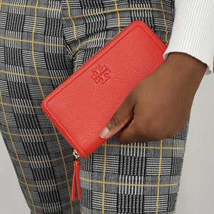 Tory Burch knows how to make bold accessories, and this wallet is no exception! A slim design in lipstick red in a classic silhouette, this wallet is great to match with the Thea clutch or with a classic black handbag for a brilliant contrast of dark and light. The lined interior has a 2 main compartments, a middle zip compartment, 2 cash pockets, and 8 card slots to keep you organized throughout the day. Make the Taylor zip wallet the next staple in your bag!