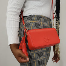 Load image into Gallery viewer, Mini bags are the perfect way to carry your essentials with the perk of an optional over the shoulder strap. With a minimalist design laid with a signature Tory Burch logo, the brilliant red color of the bag takes the spotlight in any situation! This Thea bag is iconic with its scratch resistant, high quality leather and interior compartments for superior organization. A clutch by day that can transform into a bag by night, this piece can easily transition into exactly what you need!