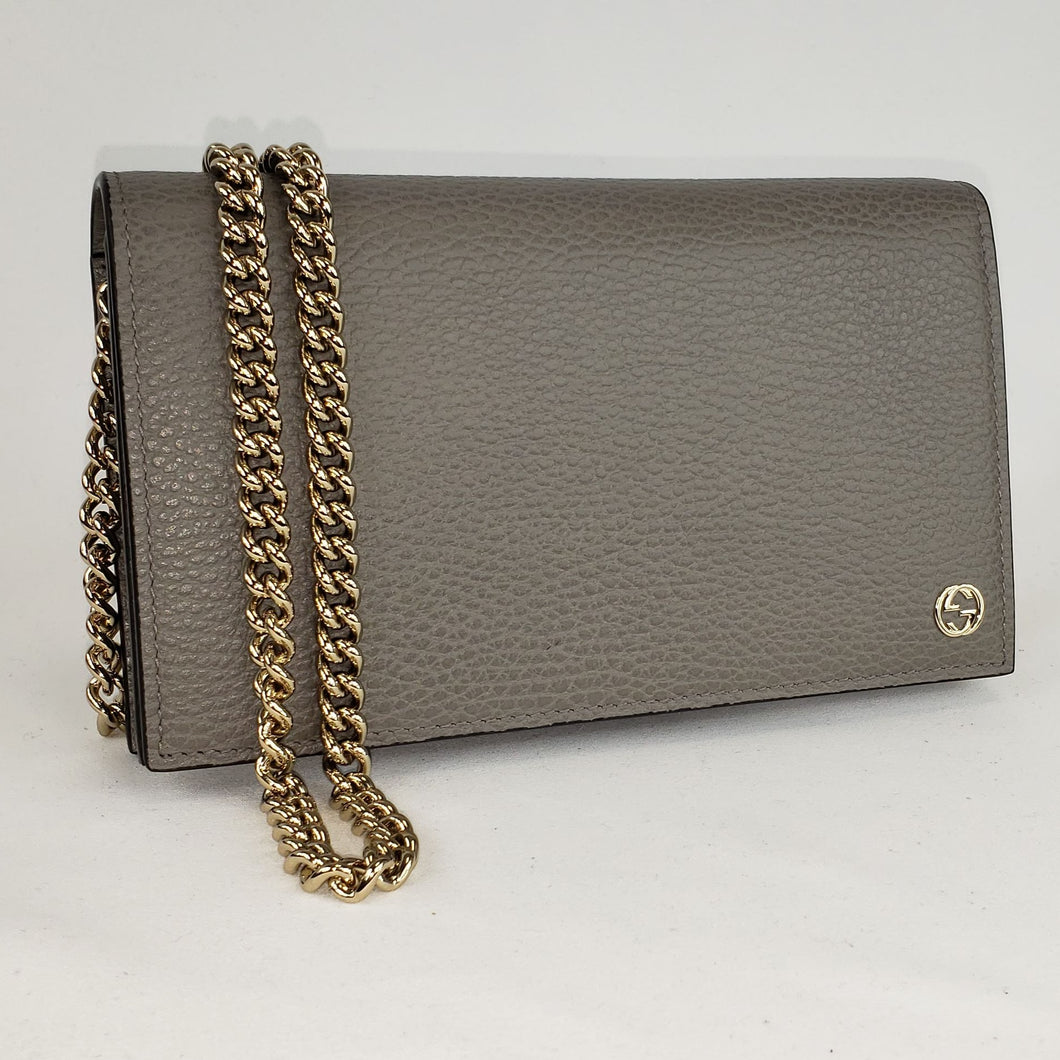 This chic wallet on chain is crafted of textured calfskin leather. The shoulder bag features a shoulder chain and a small Gucci GG emblem. It opens to a matte leather interior with a spacious zippered currency compartment, and card slot panels. This is an ideal chain wallet for keeping contents close at hand, by Gucci! The chain is removable so you can carry this bag as a wallet or wear is as a cross body.