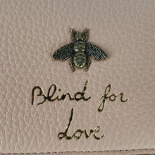 Load image into Gallery viewer, Made in Perfect Pink with an adorable gold bee accent and &quot;blind for love&quot; lettering, this small purse is a great addition to your look! Supple leather comes together with a snap closure for a simplistic, elegant design. The interior is spacious enough to hold your beloved devices, and also has 4 card slots to keep you organized. Use as a crossbody bag or remove the strap and use it as a clutch.