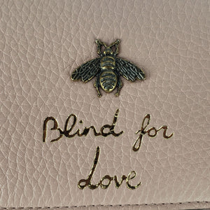 Made in Perfect Pink with an adorable gold bee accent and "blind for love" lettering, this small purse is a great addition to your look! Supple leather comes together with a snap closure for a simplistic, elegant design. The interior is spacious enough to hold your beloved devices, and also has 4 card slots to keep you organized. Use as a crossbody bag or remove the strap and use it as a clutch.