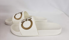 Load image into Gallery viewer, These slides are hard to come by and we can definitely see why! In a beautiful creamy white with gold accents, these shoes are the epitome of pool side footwear. With the double Gancini design, they are recognizably Ferragamo. The materials used are high quality rubber to keep you comfortable and stylish as you lounge in the summer time!