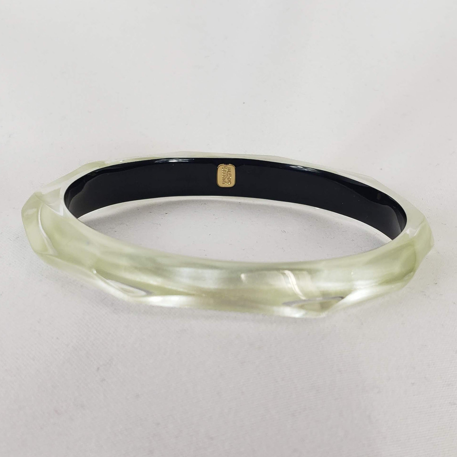 This signature faceted Lucite bangle in clear ivory is sure to impress. This bracelet can be stacked or worn alone. The bracelet is hand sculpted in the United States.  The "Alexis Bittar" tag in on the inside of the bracelet. The piece will fit most wrist sizes with a circumference of 7.5". 
