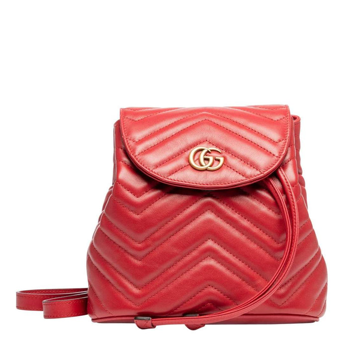 The Gucci Black Marmont Quilted Leather Backpack in Red features adjustable shoulder straps with post-stud fastening. Logo plaque at face. Fold over flap with magnetic tab fastening. Drawstring fastening at throat. Patch pocket and leather logo flag at interior. Leather lining in beige. Antiqued gold-tone hardware. Tonal stitching.