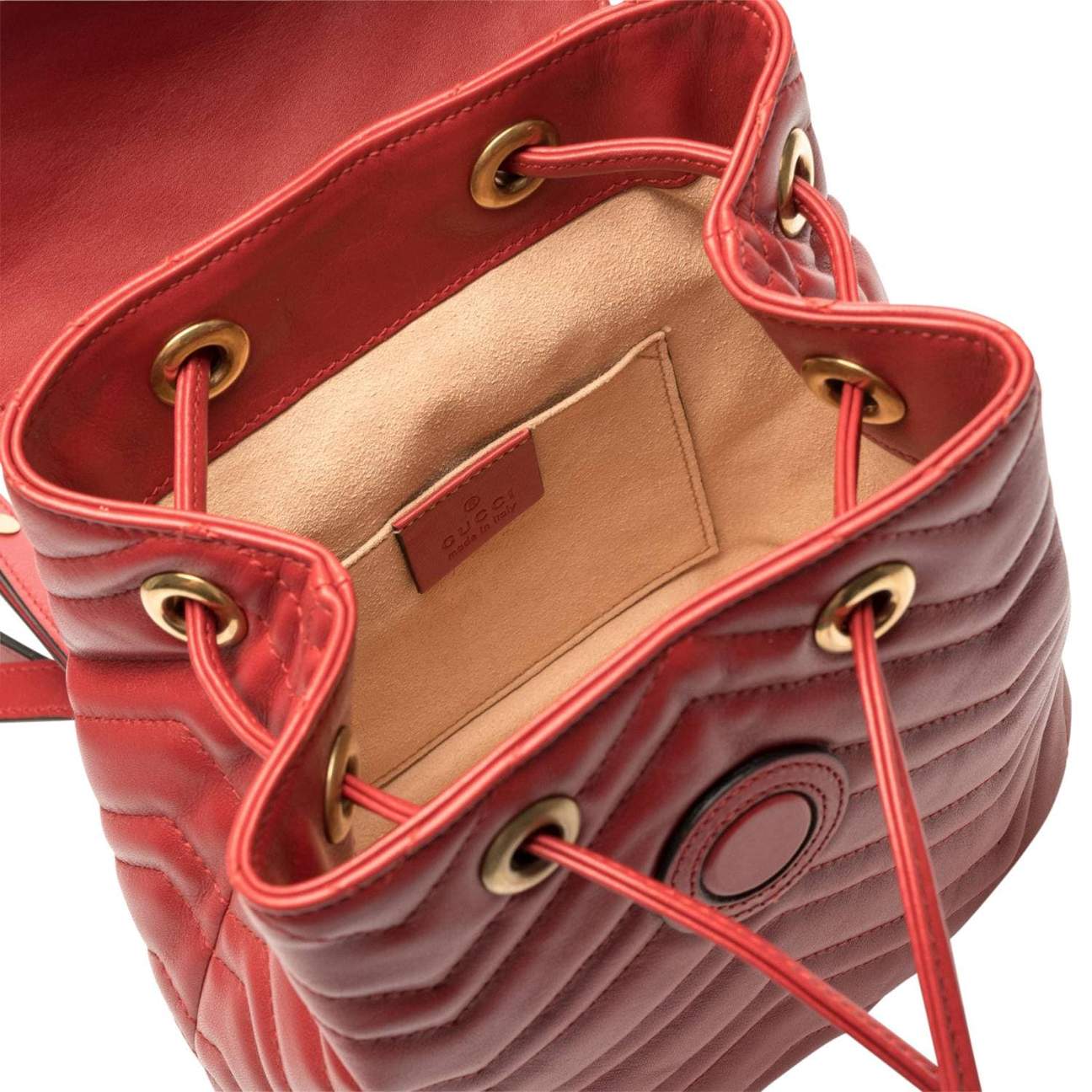 The Gucci Black Marmont Quilted Leather Backpack in Red features adjustable shoulder straps with post-stud fastening. Logo plaque at face. Fold over flap with magnetic tab fastening. Drawstring fastening at throat. Patch pocket and leather logo flag at interior. Leather lining in beige. Antiqued gold-tone hardware. Tonal stitching.
