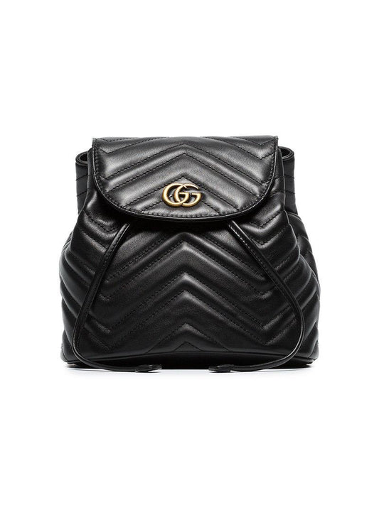 The Gucci Black Marmont Quilted Leather Backpack features adjustable shoulder straps with post-stud fastening. Logo plaque at face. Fold over flap with magnetic tab fastening. Drawstring fastening at throat. Patch pocket and leather logo flag at interior. Leather lining in beige. Antiqued gold-tone hardware. Tonal stitching.