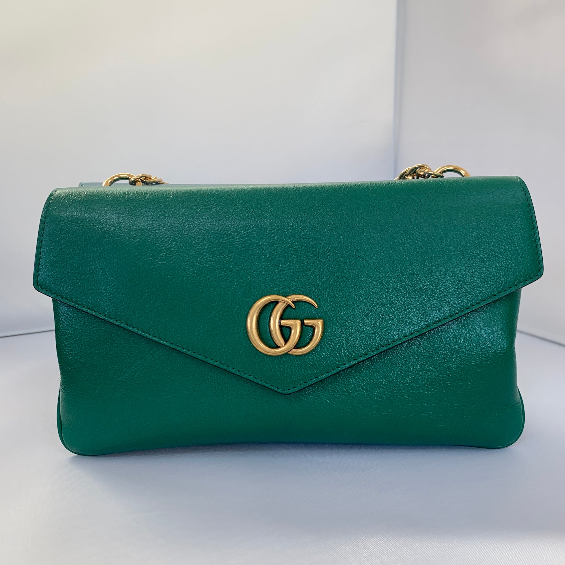 This is a two toned, double sided Gucci bag. The style is called Thiara and it looks like two envelopes back to back. One side is a mellow Robin blue. The other side is a jade green. The blue side has a jewel encrusted Raja tiger head on the magnetic clasp. The green side has the iconic double GG on the button clasp. There is a fixed Gucci gold short chain on the top and a strap is also included to make this a should bag or crossbody.