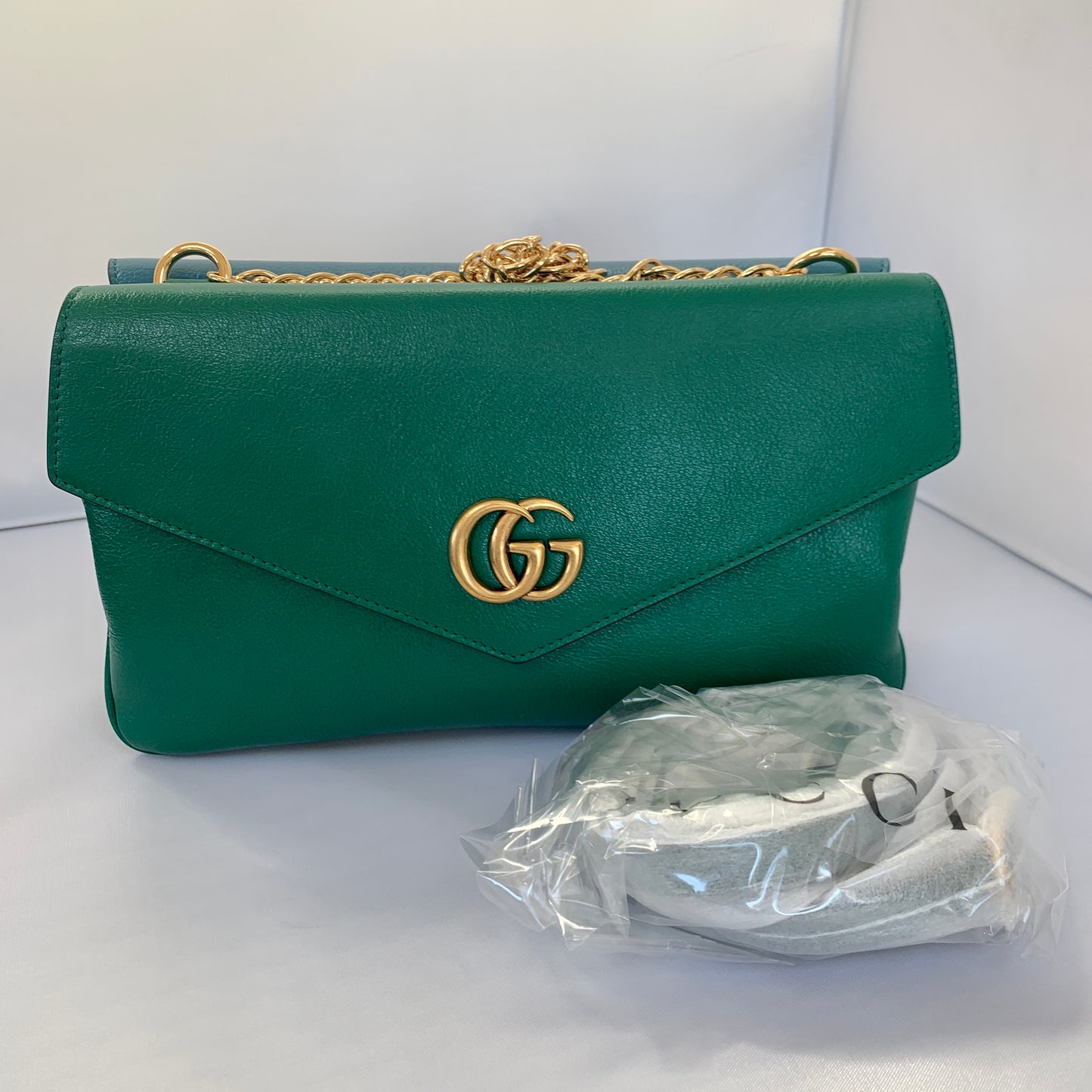 This is a two toned, double sided Gucci bag. The style is called Thiara and it looks like two envelopes back to back. One side is a mellow Robin blue. The other side is a jade green. The blue side has a jewel encrusted Raja tiger head on the magnetic clasp. The green side has the iconic double GG on the button clasp. There is a fixed Gucci gold short chain on the top and a strap is also included to make this a should bag or crossbody.