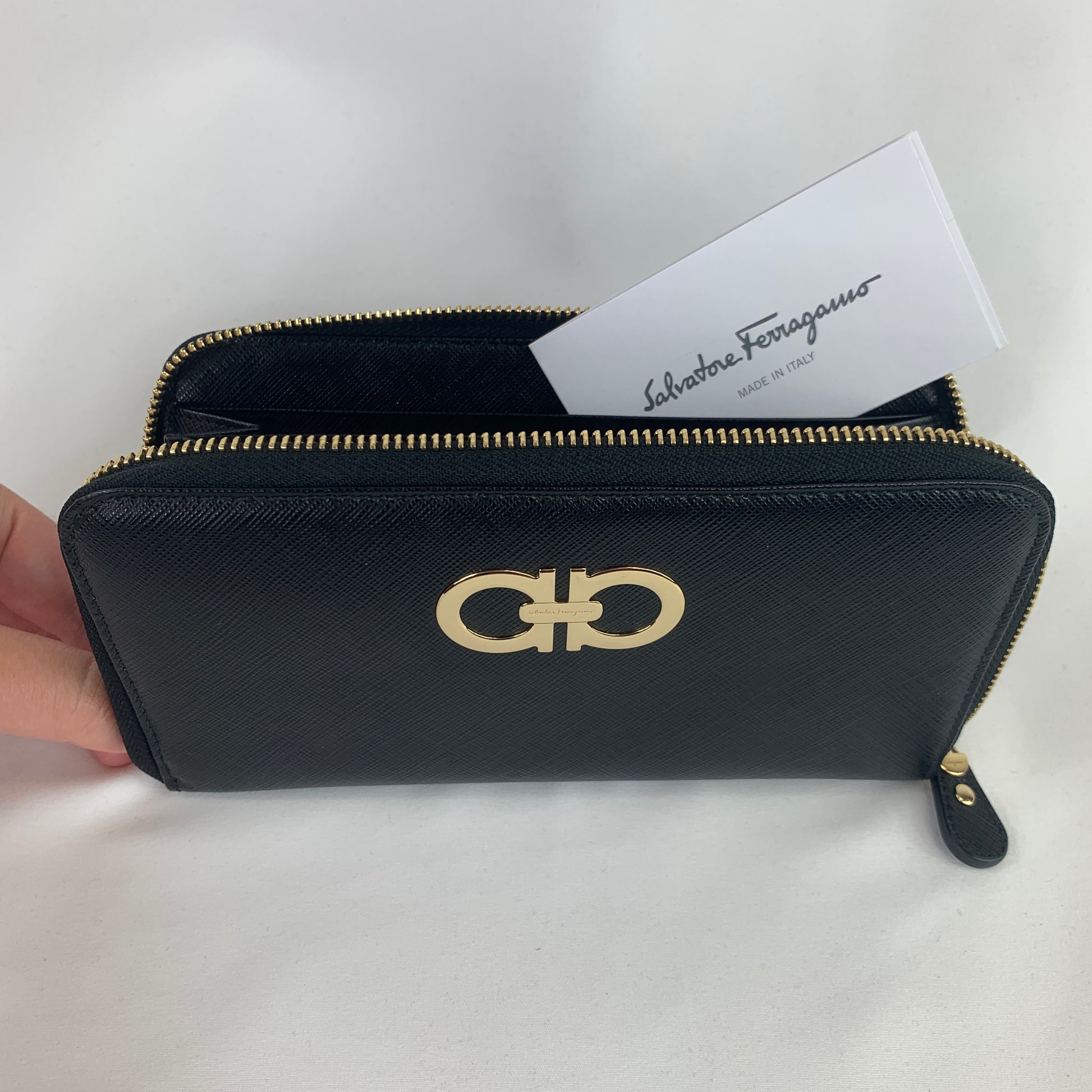 Black wallet Signature gold-toned hardware featuring Ferragamo logo 100% calf skin leather Zip around closure 3 main compartments, 2 bill slots, 8 card holders, and a zipped pouch 7.5" x 4.25" x 1" (19cm x 10.75cm x 2.5cm) Product number 61421 Made in Italy