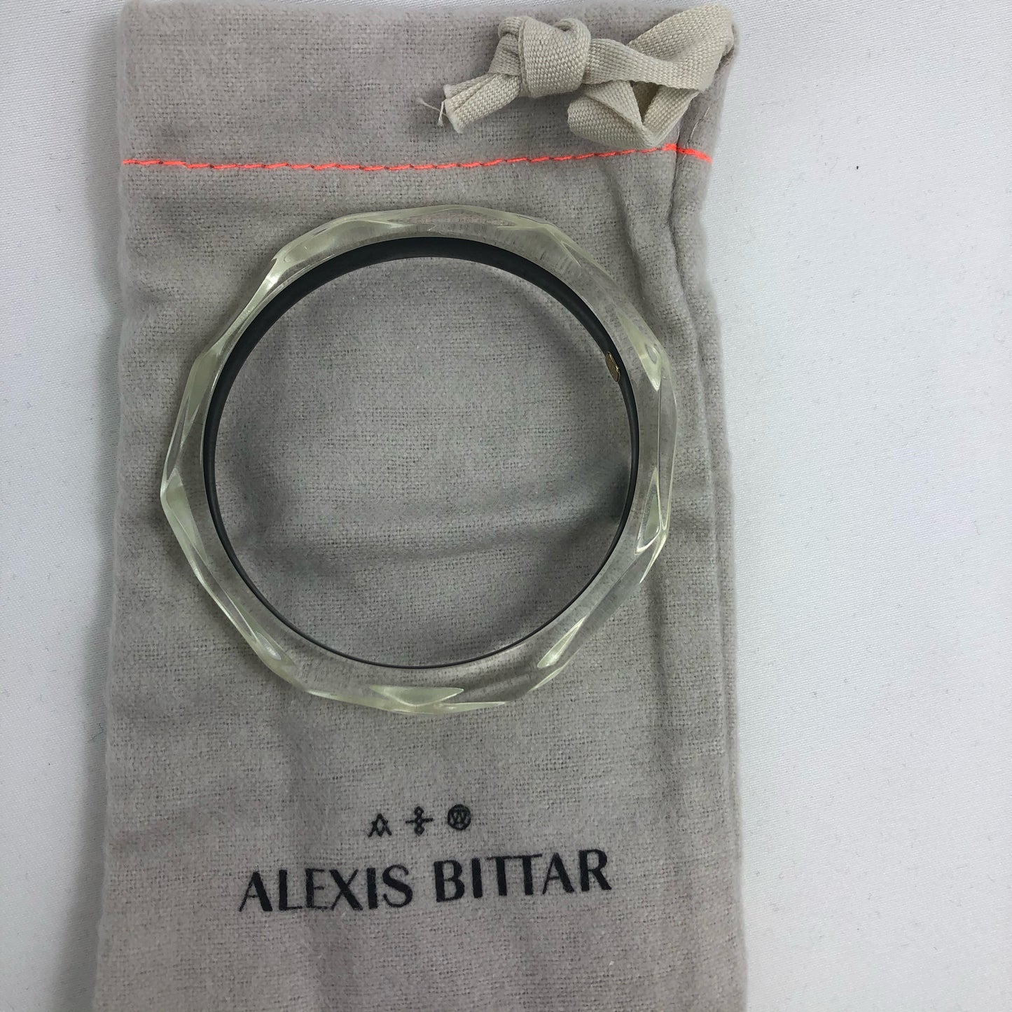 This signature faceted Lucite bangle in clear ivory is sure to impress. This bracelet can be stacked or worn alone. The bracelet is hand sculpted in the United States.  The "Alexis Bittar" tag in on the inside of the bracelet. The piece will fit most wrist sizes with a circumference of 7.5". 