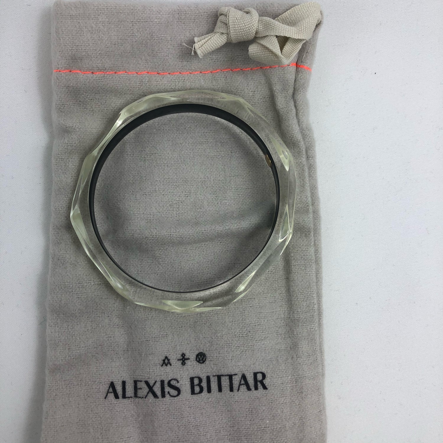 This signature faceted Lucite bangle in clear ivory is sure to impress. This bracelet can be stacked or worn alone. The bracelet is hand sculpted in the United States.  The "Alexis Bittar" tag in on the inside of the bracelet. The piece will fit most wrist sizes with a circumference of 7.5". 
