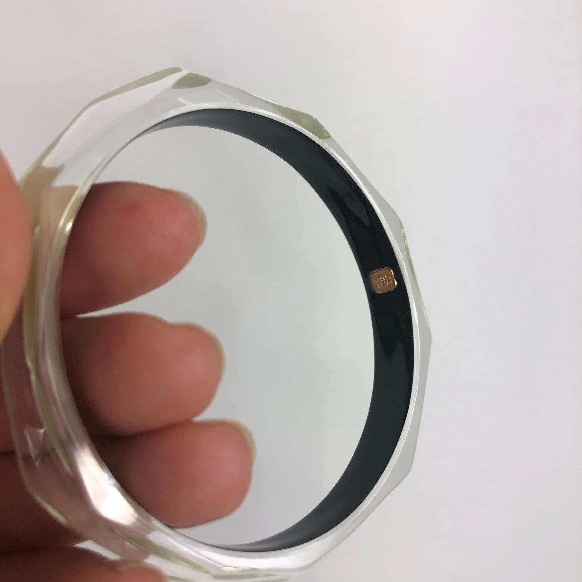 This signature faceted Lucite bangle in clear ivory is sure to impress. This bracelet can be stacked or worn alone. The bracelet is hand sculpted in the United States.  The "Alexis Bittar" tag in on the inside of the bracelet. The piece will fit most wrist sizes with a circumference of 7.5". 