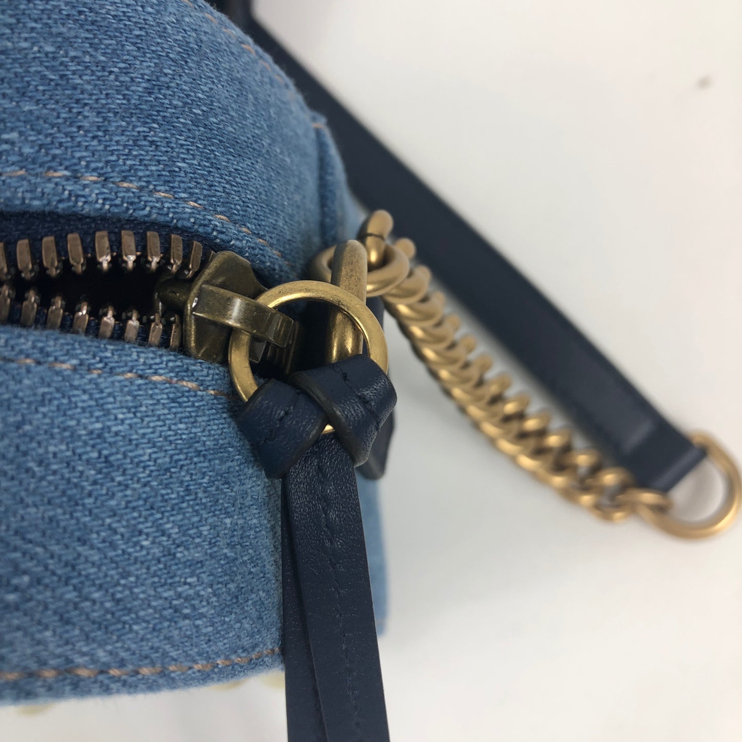 The Gucci Marmont Pearl Crossbody Bag in Denim is a modern take on a classic look. Light wash Matelassé denim Gucci Small GG Marmont Pearl Shoulder Bag with gold-tone hardware, single flat shoulder strap with chain-link accents, creme contrast stitching throughout, Running GG adornment at front face, pearl embellishments throughout exterior, coral satin interior lining, single interior slit pocket and zip closure at top. Includes dust bag. Authentic and rare handbags from Gavriel.us