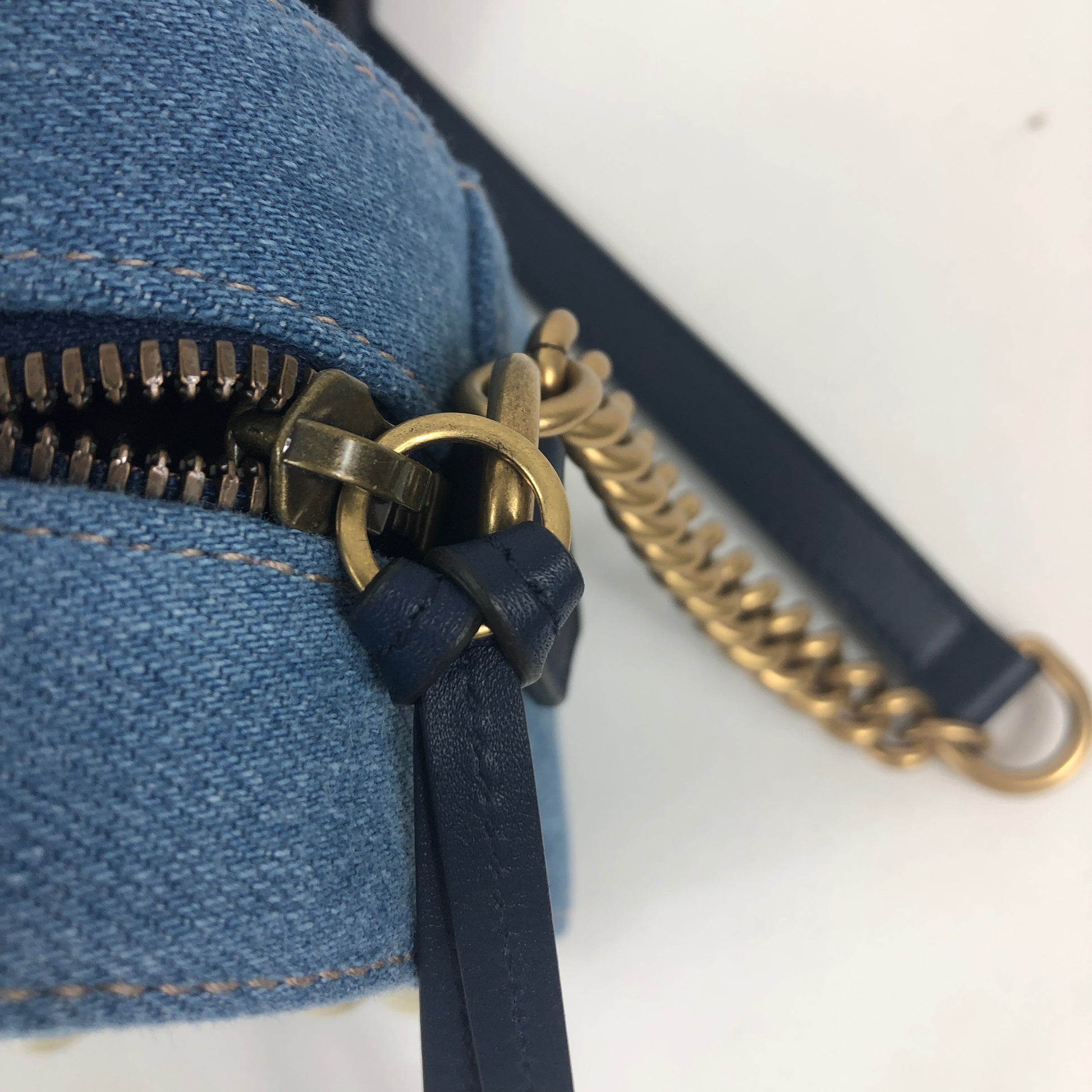 The Gucci Marmont Pearl Crossbody Bag in Denim is a modern take on a classic look. Light wash Matelassé denim Gucci Small GG Marmont Pearl Shoulder Bag with gold-tone hardware, single flat shoulder strap with chain-link accents, creme contrast stitching throughout, Running GG adornment at front face, pearl embellishments throughout exterior, coral satin interior lining, single interior slit pocket and zip closure at top. Includes dust bag. Authentic and rare handbags from Gavriel.us