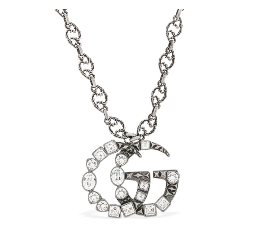 The Gucci GG Marmont Crystal Necklace In Silver is a rare and unique piece by none other than Gucci. A crystal encrusted GG pendant hangs from a delicate, intricately carved chain. A feline head charm hangs from the clasp. 