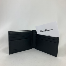 Load image into Gallery viewer, A classic black leather wallet is a staple piece that every man should have. Polished and sophisticated, a simple yet opulent bi-fold wallet will keep all your essentials organized in a compact design that can slip into your pocket. With 6 card slots, 1 full length bill slot, and 2 half sized slip pockets, this slim wallet can fit everything you need with ease. Grab this Ferragamo classic and go about your day with style and superior organization!