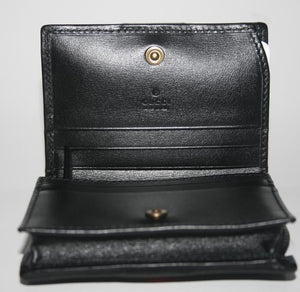 The Gucci GG Marmont Web Quilted Card Case Wallet in Black is a mini snap wallet in quilted black leather. A Double GG logo adorns the front along with a signature Gucci web. The snap closure opens to 4 card slots, a slip pocket, a bill slot with floral linen lining, and a zipped compartment. 