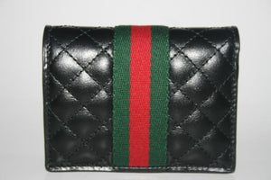 The Gucci GG Marmont Web Quilted Card Case Wallet in Black is a mini snap wallet in quilted black leather. A Double GG logo adorns the front along with a signature Gucci web. The snap closure opens to 4 card slots, a slip pocket, a bill slot with floral linen lining, and a zipped compartment. 