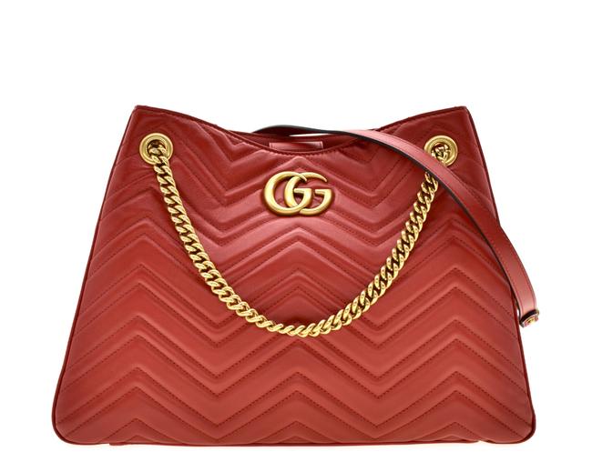 The Gucci GG Marmont Apollo Chevron Tote Shoulder Bag in Red is a unique piece that features the chevron, zig zag patterned stitching in a smooth calfskin red leather. The curved silhouette hangs from two chain shoulder straps with leather pads, while a GG logo in gold-tone hardware sits on the front and a stitched GG is on the back. 