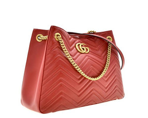 The Gucci GG Marmont Apollo Chevron Tote Shoulder Bag in Red is a unique piece that features the chevron, zig zag patterned stitching in a smooth calfskin red leather. The curved silhouette hangs from two chain shoulder straps with leather pads, while a GG logo in gold-tone hardware sits on the front and a stitched GG is on the back. 