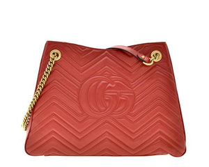 The Gucci GG Marmont Apollo Chevron Tote Shoulder Bag in Red is a unique piece that features the chevron, zig zag patterned stitching in a smooth calfskin red leather. The curved silhouette hangs from two chain shoulder straps with leather pads, while a GG logo in gold-tone hardware sits on the front and a stitched GG is on the back. 