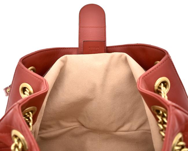 The Gucci GG Marmont Apollo Chevron Tote Shoulder Bag in Red is a unique piece that features the chevron, zig zag patterned stitching in a smooth calfskin red leather. The curved silhouette hangs from two chain shoulder straps with leather pads, while a GG logo in gold-tone hardware sits on the front and a stitched GG is on the back. 