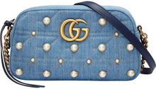Load image into Gallery viewer, The Gucci Marmont Pearl Crossbody Bag in Denim is a modern take on a classic look. Light wash Matelassé denim Gucci Small GG Marmont Pearl Shoulder Bag with gold-tone hardware, single flat shoulder strap with chain-link accents, creme contrast stitching throughout, Running GG adornment at front face, pearl embellishments throughout exterior, coral satin interior lining, single interior slit pocket and zip closure at top. Includes dust bag. Authentic and rare handbags from Gavriel.us
