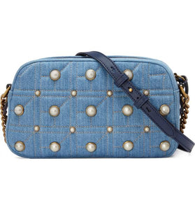 The Gucci Marmont Pearl Crossbody Bag in Denim is a modern take on a classic look. Light wash Matelassé denim Gucci Small GG Marmont Pearl Shoulder Bag with gold-tone hardware, single flat shoulder strap with chain-link accents, creme contrast stitching throughout, Running GG adornment at front face, pearl embellishments throughout exterior, coral satin interior lining, single interior slit pocket and zip closure at top. Includes dust bag. Authentic and rare handbags from Gavriel.us