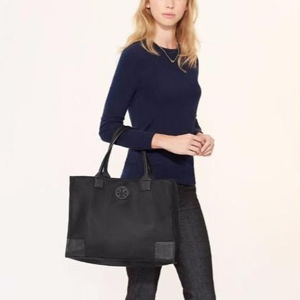Black Ella tote bag Nylon bag  Nylon interior lining with Tory Burch emblem pattern Leather Tory Burch logo, reenforced corners, and dual handles Open top with magnetic snap closure Snap closures on either sides for extended space 1 zippered pocket, 2 slip pockets. 12.5" x 16.75" x 5.75" Product number 555280219 Imported